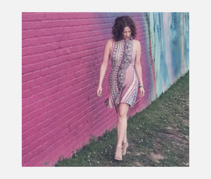 woman walking in dress next to pink wall